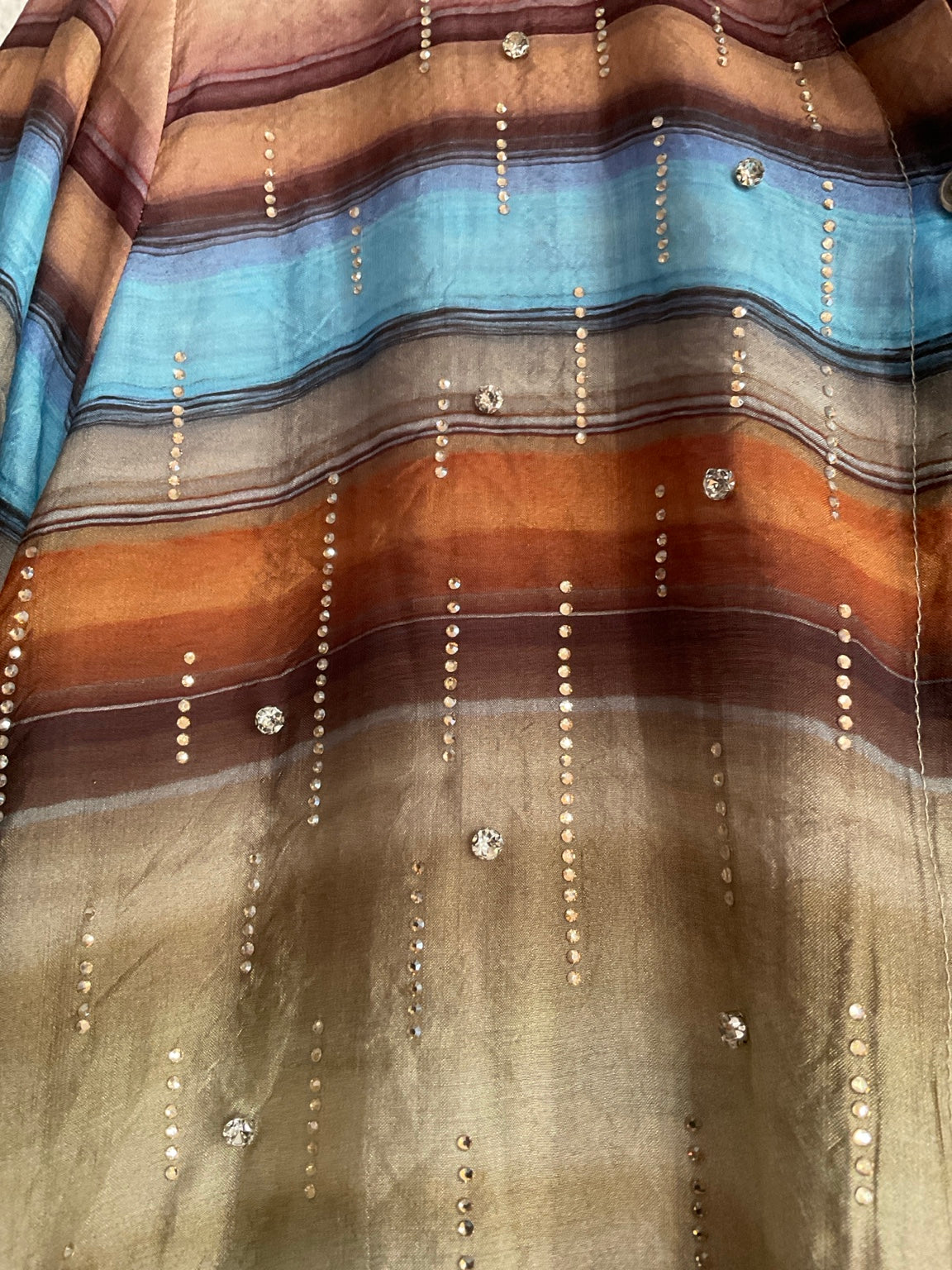 Detalle de rayas y aplicaciones brillantes de la camisa multicolor