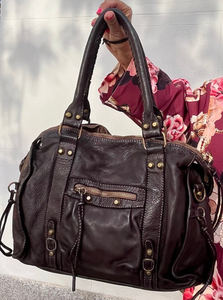 Bolso de piel marrón chocolate con aire motero, vista frontal completa.