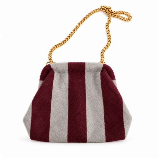 Bolso pouch de rayas burdeos y gris con cadena dorada sobre fondo blanco