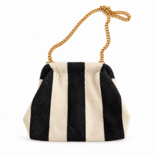 Bolso pouch de rayas negro y crudo con cadena dorada sobre fondo blanco