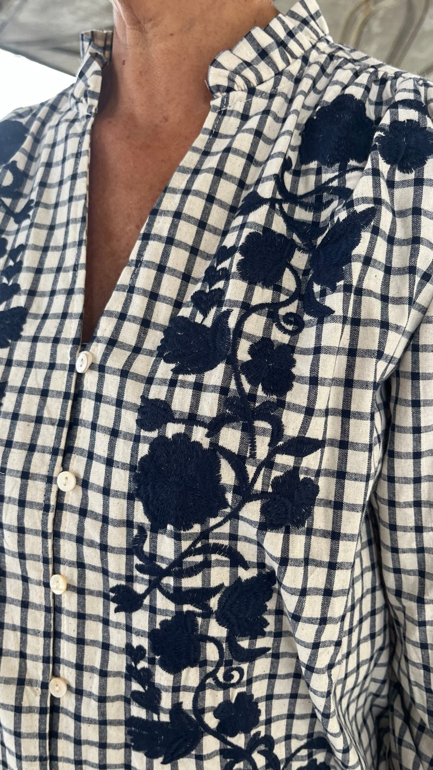 Primer plano bordado floral azul marino en camisa de cuadros