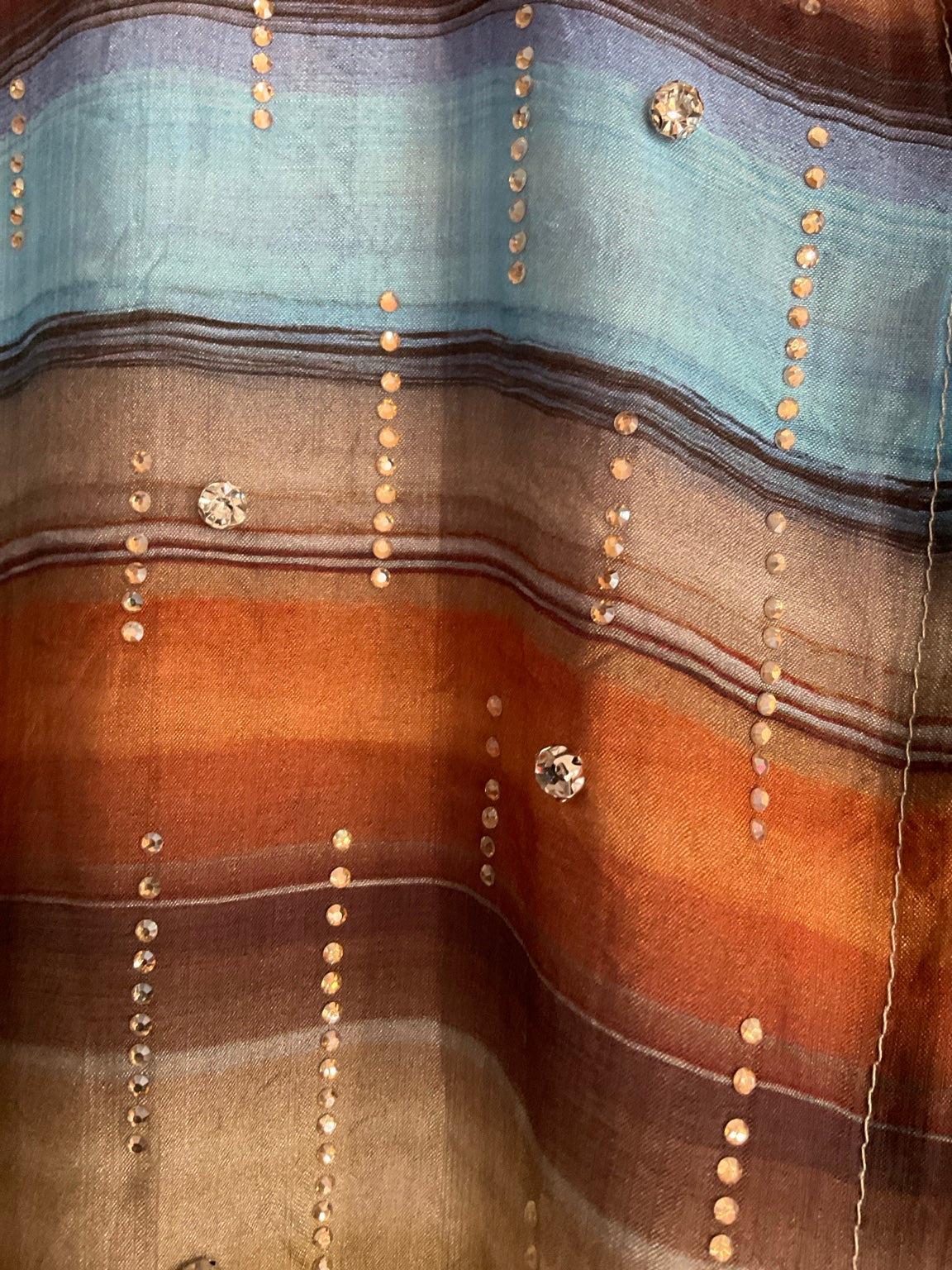 Primer plano del tejido y pedrería de la camisa multicolor