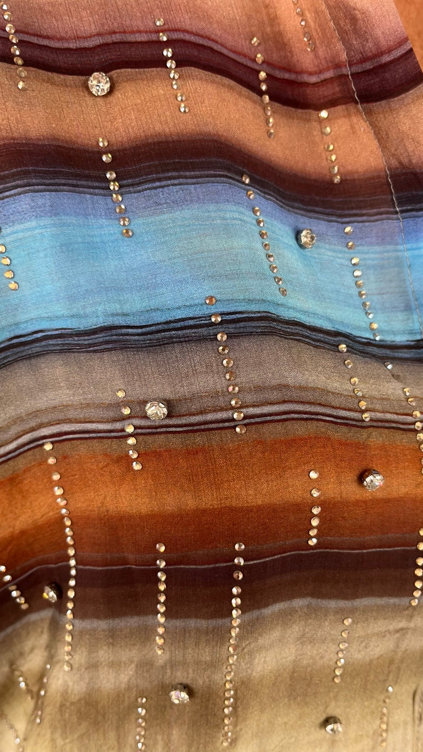Detalle del tejido y aplicaciones brillantes de la camisa multicolor
