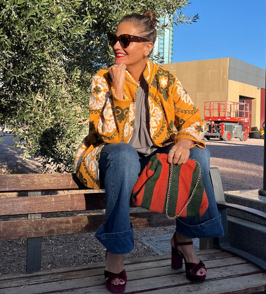 Look con chaqueta India mostaza bordada, vaqueros y bolso de rayas