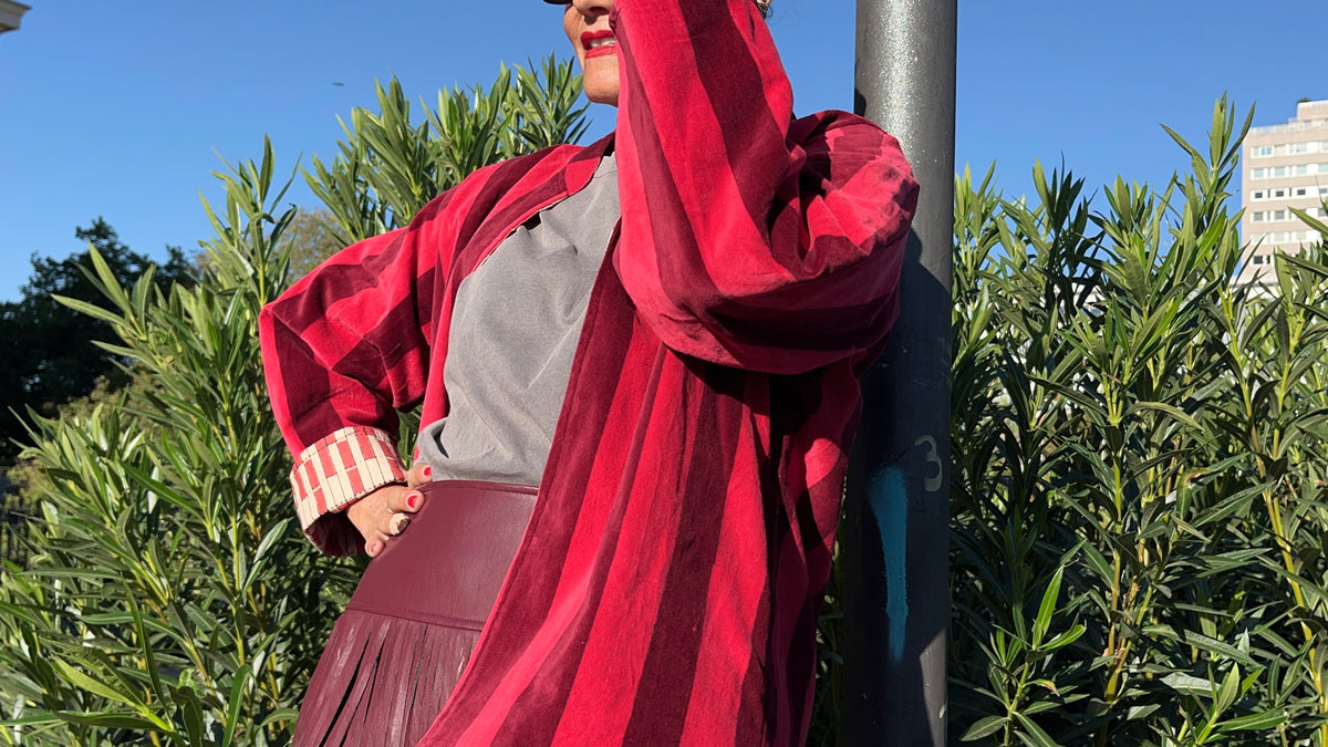 Detalle de la chaqueta de terciopelo de rayas rojas y del puño vuelto con estampado de cuadros.