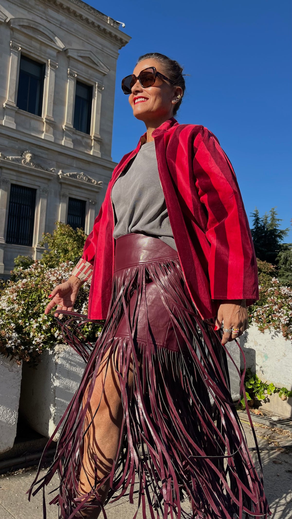 Vista frontal de la chaqueta de terciopelo de rayas rojas combinada con falda larga de flecos.