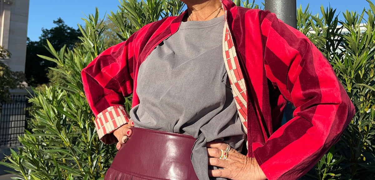 Modelo con chaqueta de terciopelo de rayas rojas en una pose relajada sobre un banco.