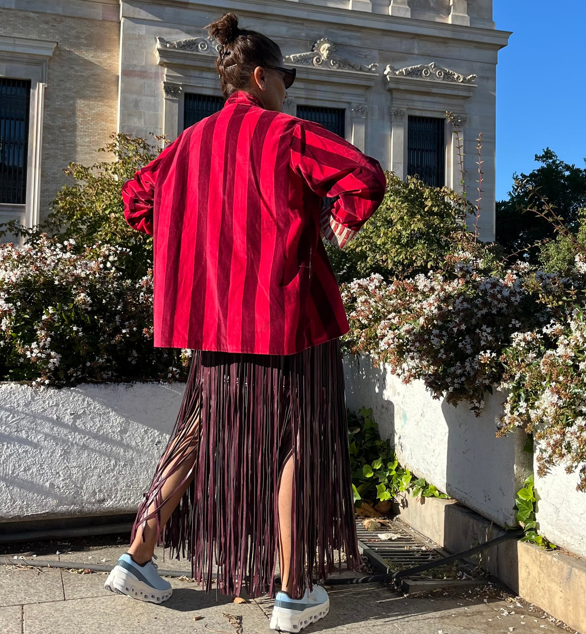 Vista trasera de la chaqueta de terciopelo de rayas rojas puesta por una modelo.