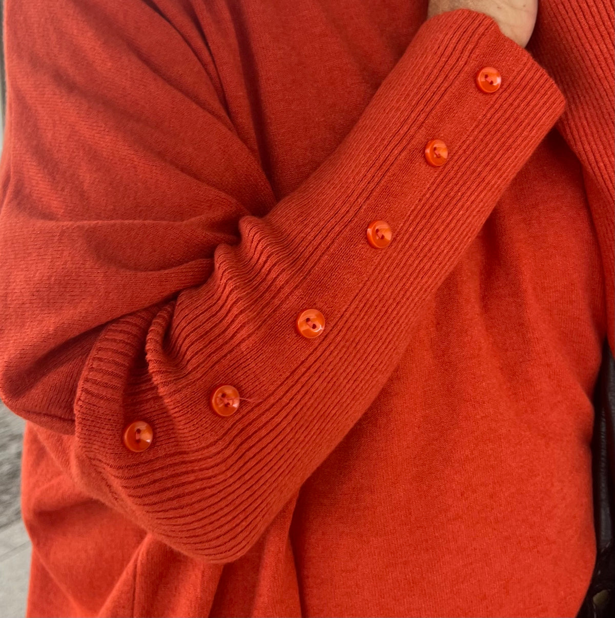 Detalle de los botones tono naranja en el puño del jersey