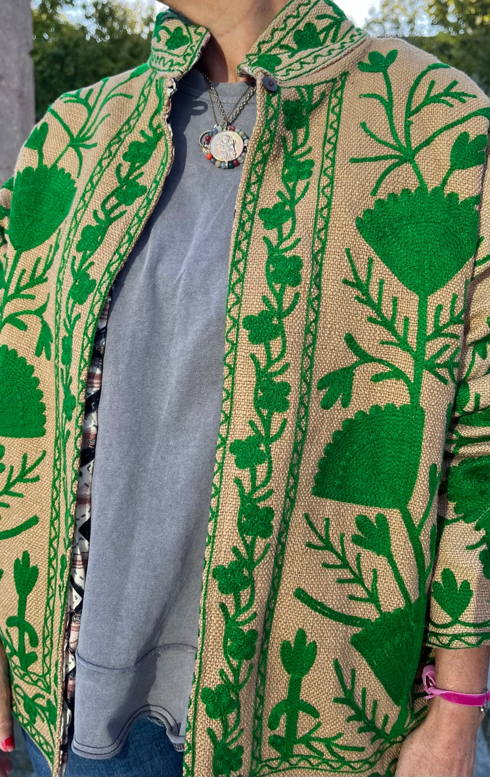 Detalle frontal de chaqueta beige de algodón con bordado verde