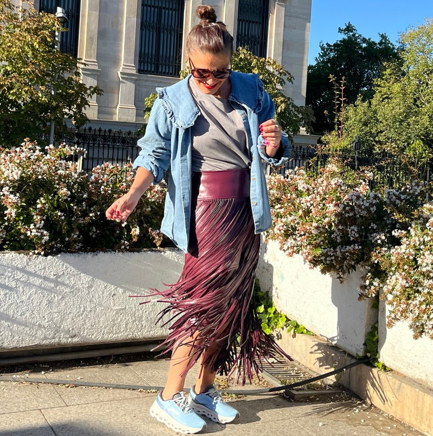 Falda berenjena con flecos largos en movimiento, combinada con chaqueta vaquera.