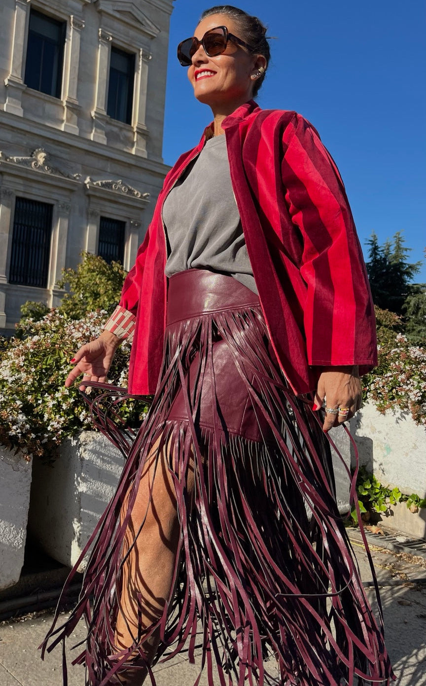 Falda berenjena con flecos largos combinada con chaqueta roja.