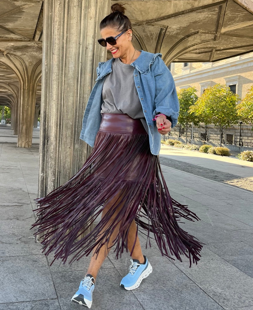 Falda berenjena de flecos largos con chaqueta vaquera, en un look de cuerpo entero.