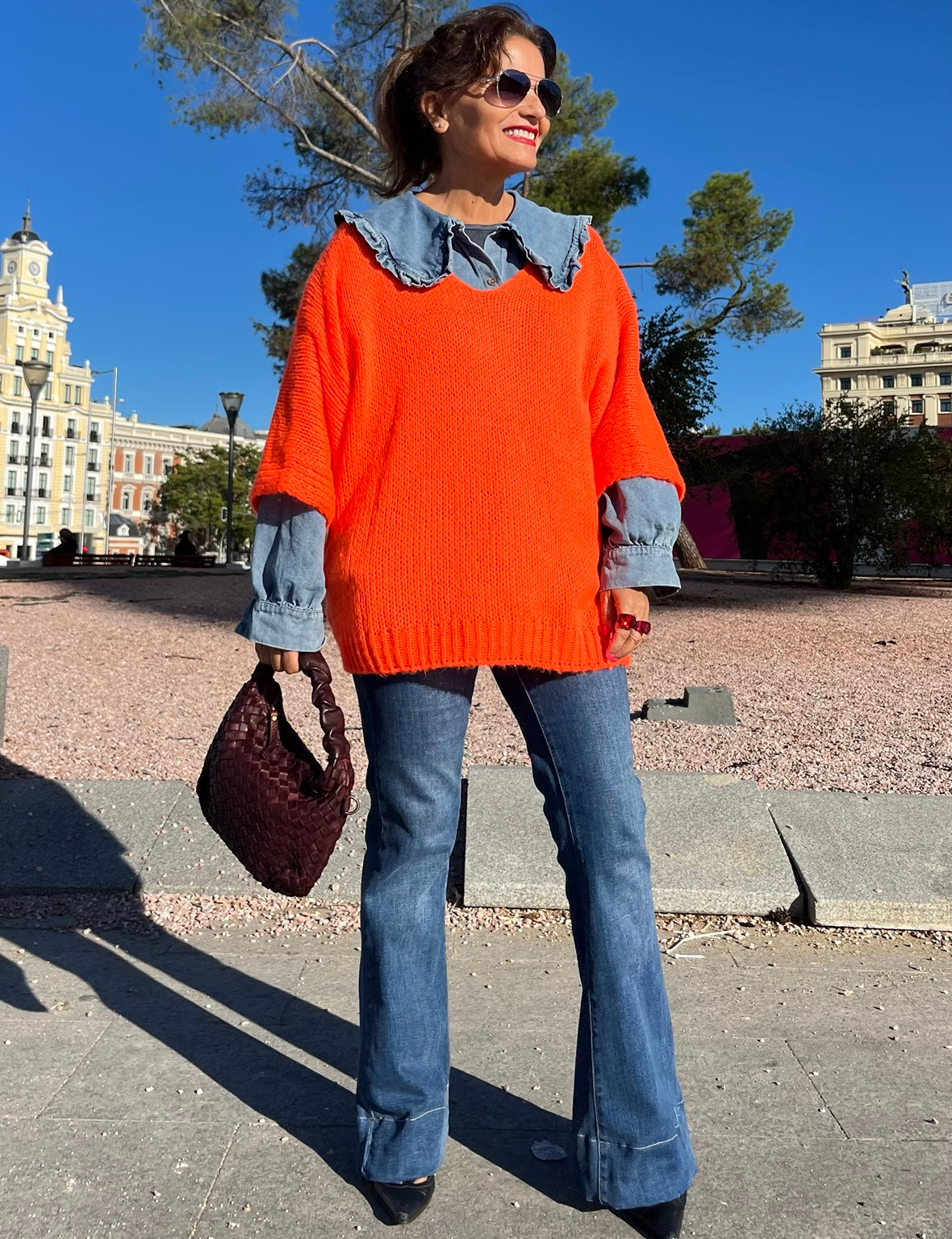 Jersey naranja de punto con camisa vaquera y bolso burdeos trenzado, look completo La Canaria
